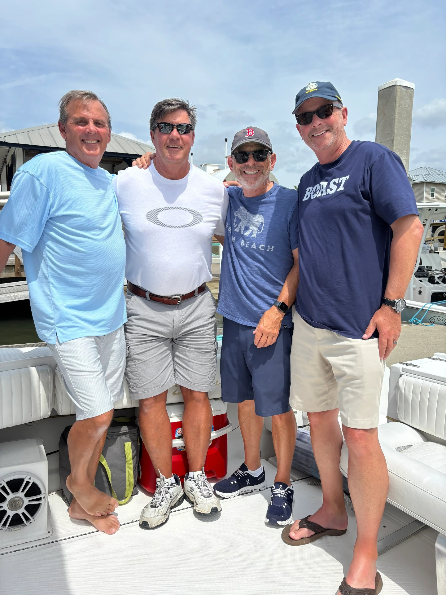 Four guests standing together in the Sweet Melissa's cockpit at the dock, arms round each other