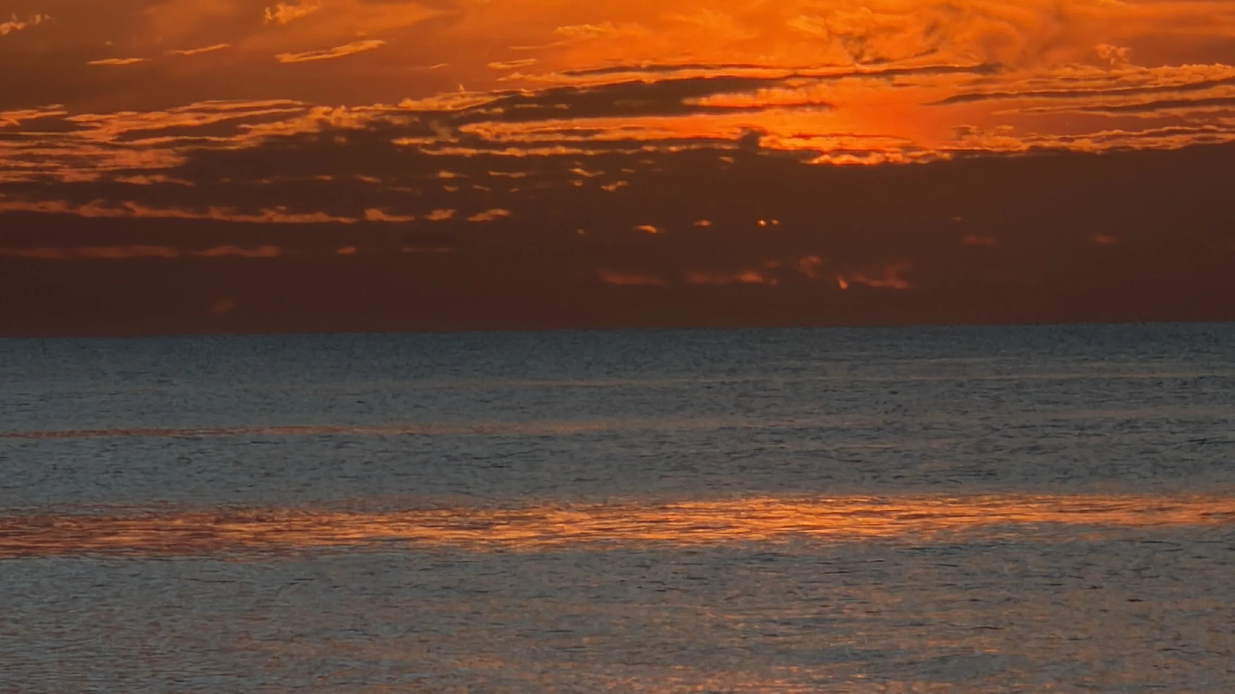 Banded orange cloud over open Gulf water at sundown